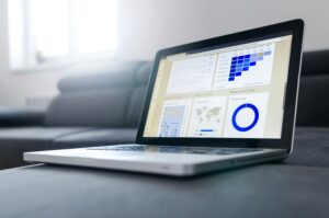 Notebook aberto em cima de um estofado exibindo relatórios de análise de cohort e gráficos financeiros na tela, exemplificando a tecnologia usada por uma fintech de crédito.