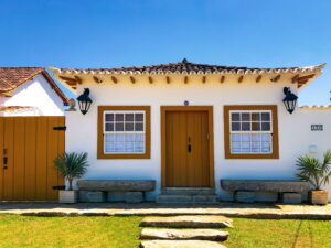 Fachada de casa residencial colonial branca com portas mostarda e telhado de barro, ilustrando o patrimônio usado como garantia na modalidade de home equity.